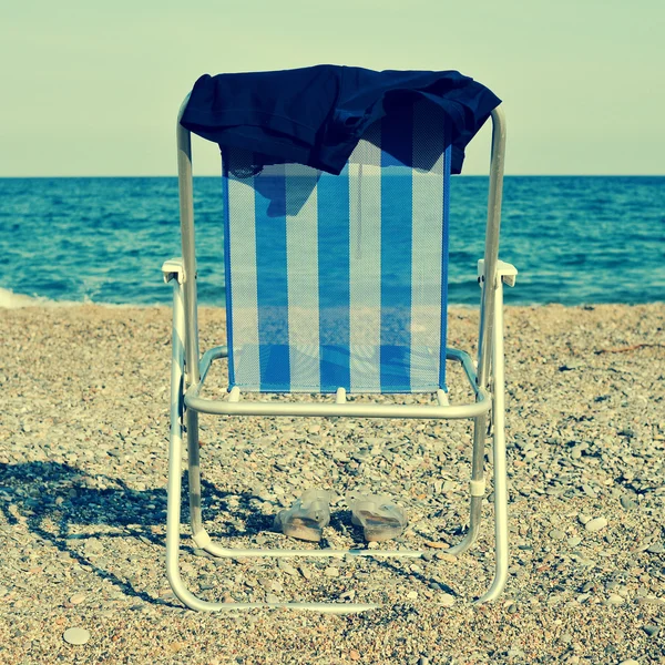 Strandstoel en man zwembroek op het strand, met een retro-effect — Stockfoto