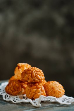 İspanya Katalonya 'nın tipik bir şekerlemesi olan Panellet de Pinyo yığınına yakın plan. Azizler Günü' nde geleneksel olarak yenir. Gri ahşap bir masa üzerine örülmüş bir altlığa yerleştirilir.