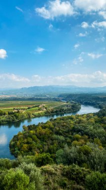 Ebro Nehri, arka planda Serra de Cardo ve Els Ports dağ sıraları ile İspanya 'nın Miravet kentinden geçmekte, mobil hikayeler veya akıllı telefon duvar kağıdı olarak kullanmak için dikey bir formatta