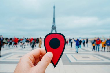 Fransa, Paris 'teki Eyfel Kulesi' ni gösteren kırmızı bir işaret taşıyan genç beyaz bir adamın eli.