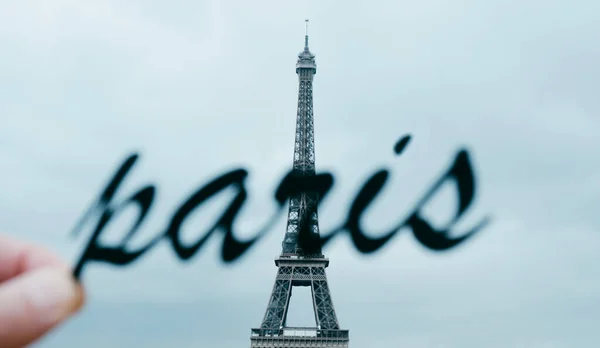 在法国巴黎的埃菲尔铁塔前 一个拿着 这个词的轮廓的年轻人的手 以全景的形式被用作网页横幅或标题 — 图库照片