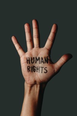 Koyu gri arka planda insan hakları yazılı metni olan bir adamın açık eline yakın çekim.