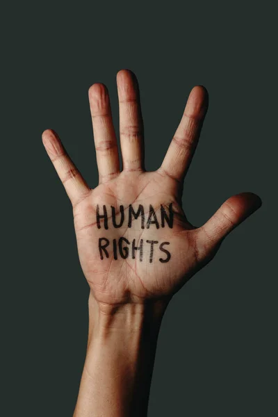 一个人张开的手的特写镜头 手上拿着写着人权的文字 背景是深灰色的 — 图库照片
