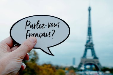 Elinde konuşma balonu olan genç bir adamın yakın çekimi. Fransa 'nın Paris kentindeki Eyfel Kulesi' nin önünde Fransızca Fransızca yazıyor musunuz?