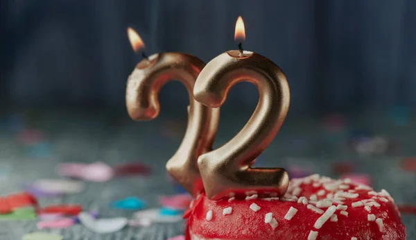 点燃的金色数字形状的蜡烛 在一个红色泡沫的小蛋糕上 在一个灰色的乡村木桌上 点缀着22号蜡烛 用全景形式 用作横幅或标题 — 图库照片