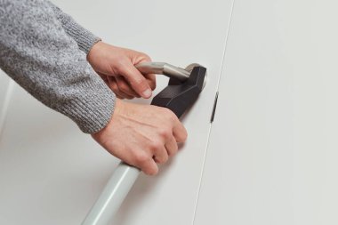 Genç bir beyaz adamın, evinin kapısını bir kapı engelleme çubuğuyla kapatırken görüntüsü.