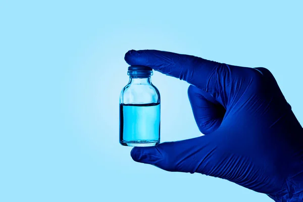 青い手術用手袋を着用し青い液体のバイアルを示す医療や研究室の労働者の閉鎖 — ストック写真