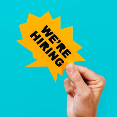 Sarı kağıt konuşma baloncuğu tutan bir adamın mavi arka planda, kare şeklinde bir konuşma balonu.