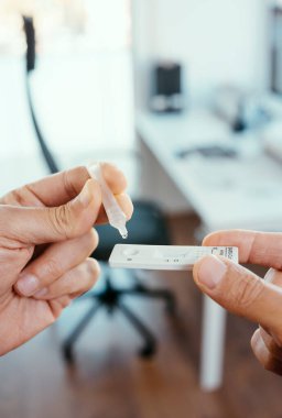 Genç bir adam kendi örneğini ofisteki kovid 19 antijen test cihazına yerleştiriyor.