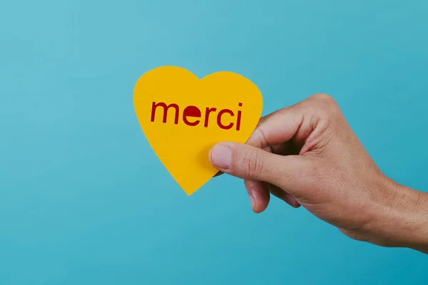 Крупный План Человека Желтым Сердцем Руке Текстом Спасибо Написано Французски — стоковое фото