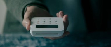 Kafkasyalı bir adamın elinde kablosuz ödeme terminali olan, web pankartı ya da başlık olarak kullanılacak panoramik bir formatta yakın plan fotoğrafı.