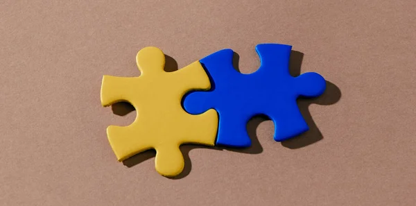 Hoge Hoek Weergave Van Twee Puzzelstukjes Geschilderd Geel Blauw Die — Stockfoto