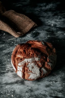 Koyu gri kumaş bir yüzey üzerinde yuvarlak bir kamut buğday ekmeği.