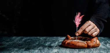 Paskalya pazartesileri yenen geleneksel bir İspanyol pastası olan pembe tüy ile dekore eden bir adamın resmi. Haşlanmış yumurtalarla süslenmiş, web pankartı olarak kullanılacak panoramik bir formatta.