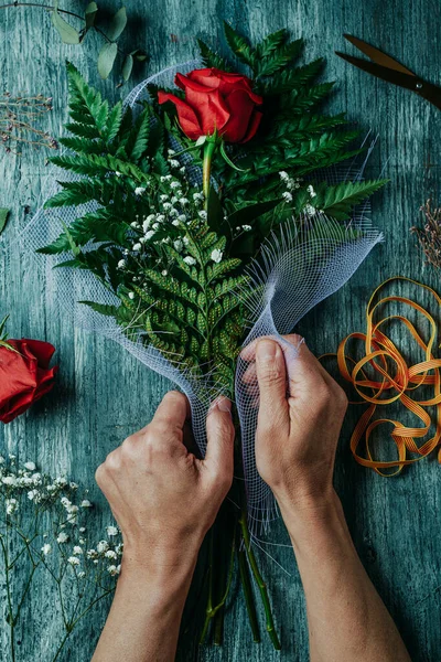 カタルーニャ語で 聖ジョージの日 を意味するサンジョルディの赤いバラの花束を並べ男の高い角度ビュー カタルーニャの赤いバラを与えるために伝統であるとき 灰色の素朴なテーブルの上に — ストック写真