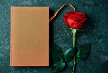 Katalan bayrağıyla kahverengi bir kitabın yüksek açılı görüntüsü ve Katalonya, İspanya 'da kırmızı gül ve kitap vermek gelenek haline geldiğinde Aziz George Günü' nün Katalan adı olan Sant Jordi için kırmızı bir gül.