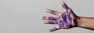 Mor boya lekeleri olan, gri bir arka planda, web pankartı ya da başlık olarak kullanılacak panoramik bir formatta bir adamın eli.