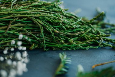Bir avuç çiğ kuşkonmaz, siyah bir taş yüzeyde hafifçe aydınlatılmış.