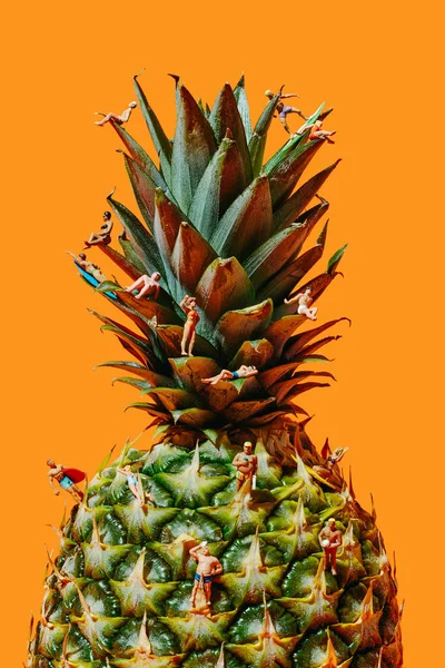 Bazı Minyatür Insanlar Farklı Eylemlerle Ananasın Üzerinde Turuncu Bir Arka — Stok fotoğraf