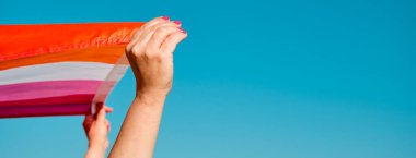 Kafkasyalı bir kadının gökyüzünde lezbiyen gururu bayrağı sallarken, panoramik bir formatta web pankartı ya da başlığı olarak kullanırken.