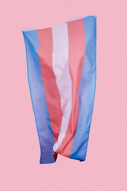 a transgender pride flag waving in the air on a pink background