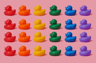 several rubber ducks of different colors forming the rainbow flag on a pink background clipart