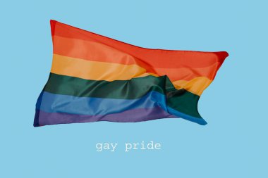 Mavi arka planda sallanan renkli gökkuşağı gurur bayrağı ve metin gay gururu