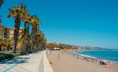 Malaga, İspanya - 26 Mayıs 2022: İspanya 'nın Malaga kentindeki La Malagueta plajında güneşli bir günün güzel havasının keyfini çıkaran birçok insanın olduğu bir gezinti manzarası