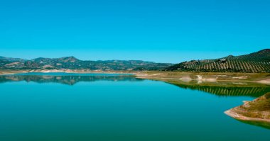 İspanya 'nın Endülüs kentindeki Iznajar rezervuarında güneşli bir bahar gününde panoramik bir manzara.
