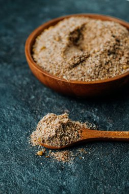 Ahşap bir kâse ve ahşap bir kaşık ile acai, çilek ve muzdan yapılmış, gri taştan bir yüzey üzerinde vejetaryen kahvaltı hazır karışımı.