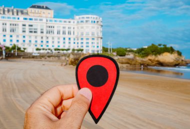 Biarritz, Fransa 'da La Grande Plage plajını gösteren kırmızı bir işaret taşıyan bir adamın eli.