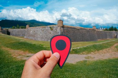 closeup of the hand of a man holding a red marker pointing the Citadel of Jaca, in Jaca, in the province of Huesca, Aragon, Spain, in a sunny summer day