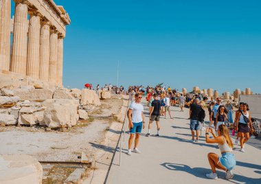 Atina, Yunanistan - 30 Ağustos 2022: Yunanistan 'ın Akropolis kentinde, ünlü Parthenon' un kalıntıları önünde genç bir bayanın fotoğrafını çeken genç bir bayan