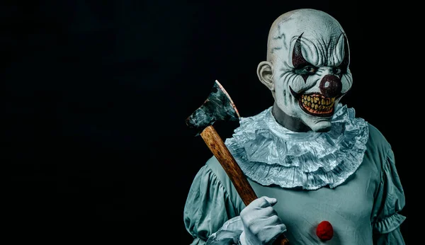 closeup of a creepy bald evil clown holding a dirt old axe with stains of blood, staring at the observer, against a black background with some blank space on the left