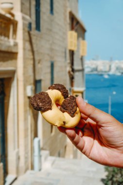 Bir yaz günü Malta 'nın Valletta kentindeki eski bir sokakta elinde Qaghaq tal-ghasel, İngilizce' de bal halkası olarak da bilinir.