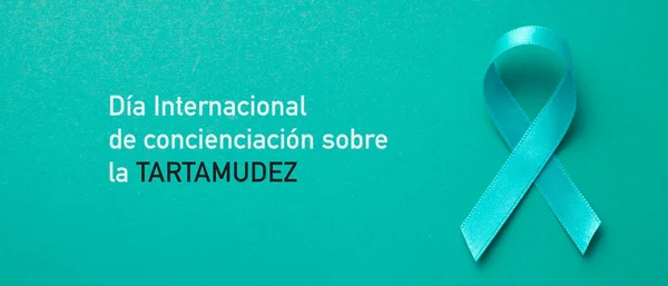 an aquamarine awareness ribbon supporting those who stutter and the text international stuttering awareness day written in spanish, in a panoramic format to use as web banner