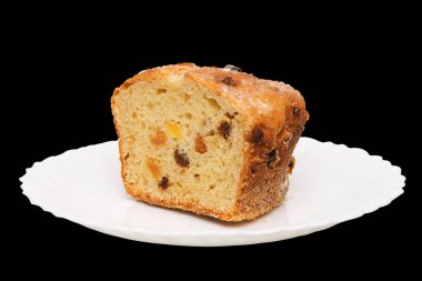 Siyah arka planda izole edilmiş beyaz tabakta bir dilim meyveli kek.