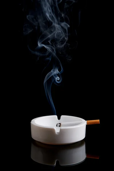 Cigarrillo en un cenicero en negro — Foto de Stock