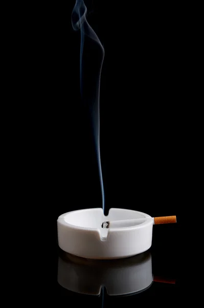 Cigaretu v popelníku na černém pozadí — Stock fotografie