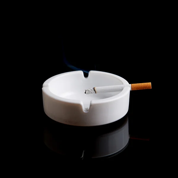 Сигарети в попільничці на чорному — стокове фото