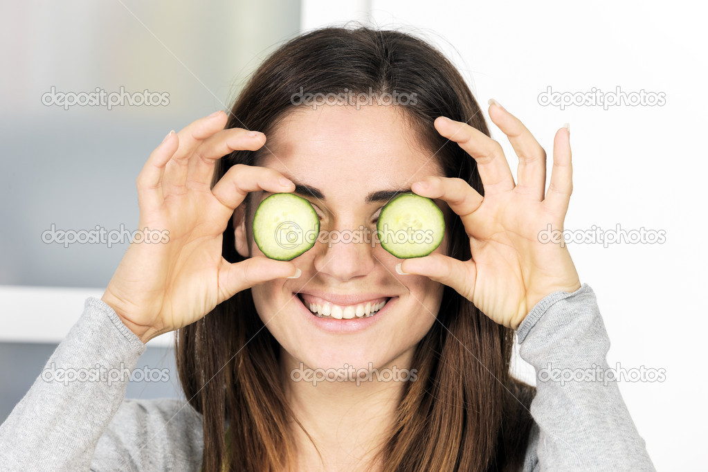 Woman holding slice of cucumber