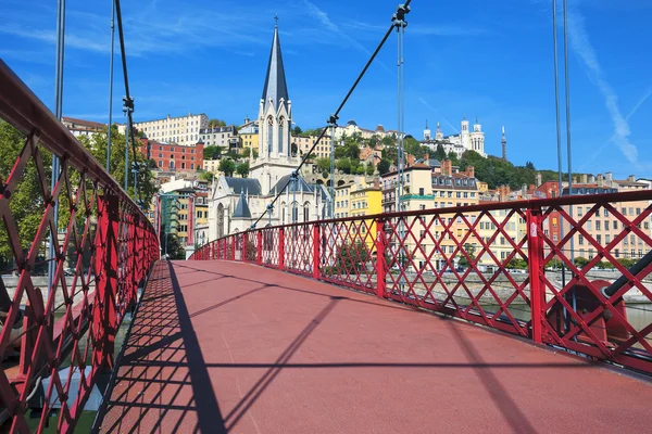 Красный пешеходный мост на реке Саоне и церковь — стоковое фото