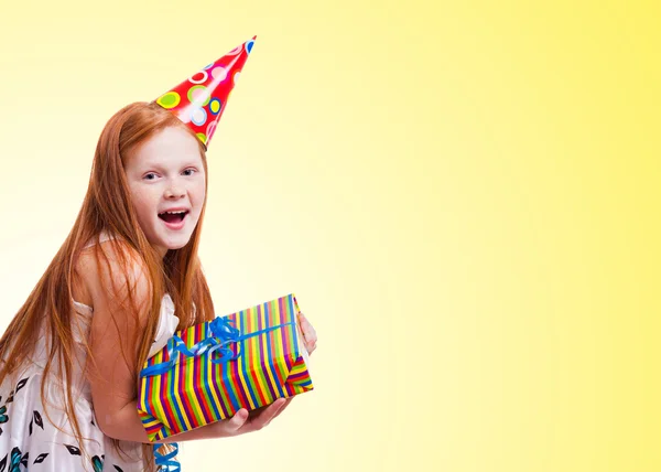 Menina feliz com caixa de presente no fundo amarelo — Fotografia de Stock