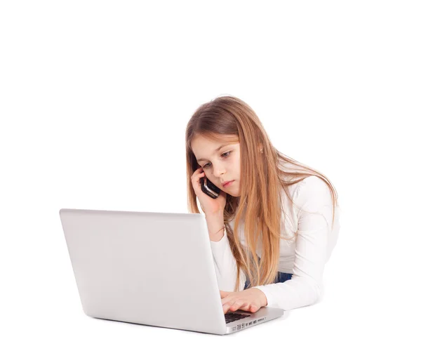 ノート パソコンやモバイル フォンでの作業床に横になっている小さな女の子 — ストック写真