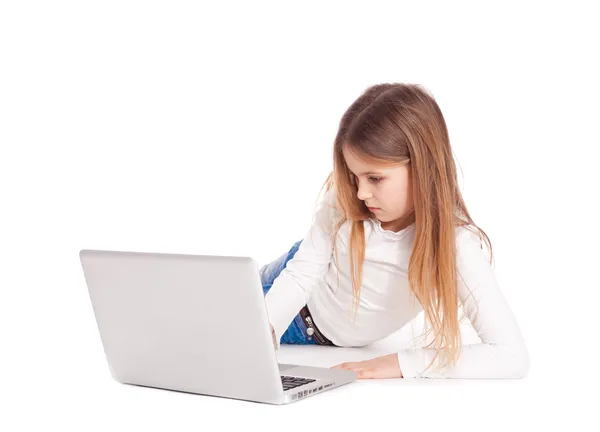 Little girl lying on floor working with a laptop — Stock Photo, Image