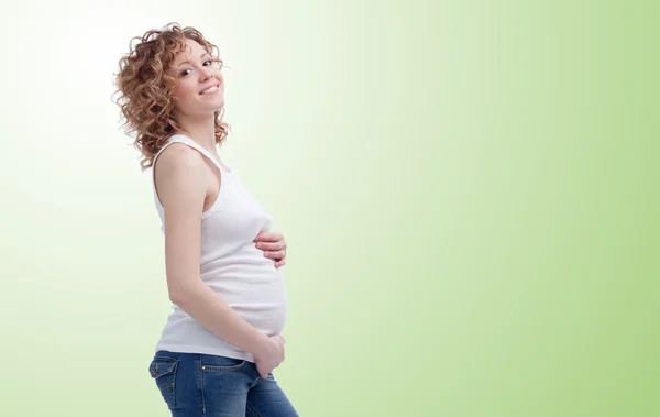 Incinta capelli ricci donna su sfondo verde — Foto Stock