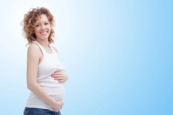 Femme enceinte souriante sur fond bleu — Photo