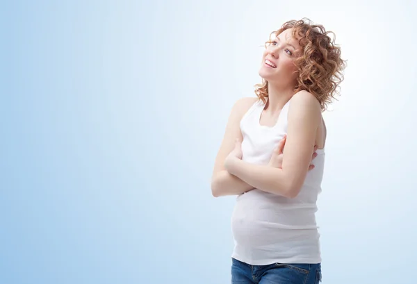 Sonhando feliz mulher grávida no fundo azul — Fotografia de Stock