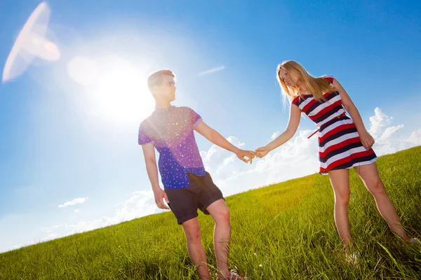 Пара держащихся за руки и идущих по зеленому полю — стоковое фото