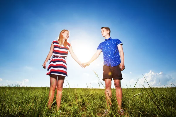 Couple holding hands and walking in green field — Stock Photo, Image